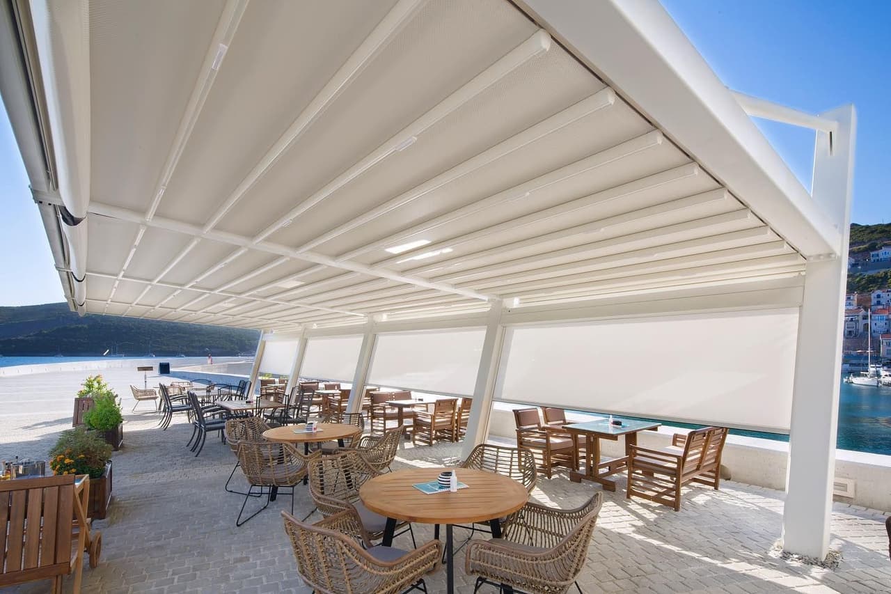 Retractable pergola over a sunlit waterfront terrace